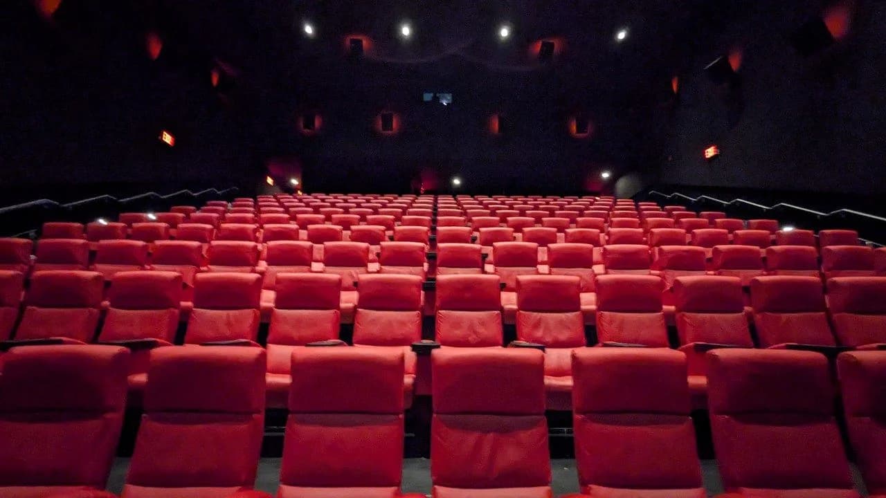 An empty movie theater with rows of red seats; no people present