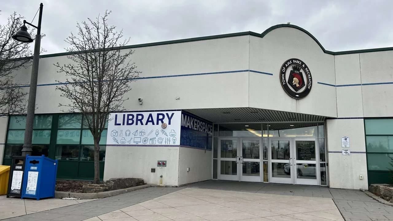 Exterior of the McLean Community Centre in Ajax, Ontario — the McLean Branch entrance with library and makerspace signage, plaza in front; no people visible