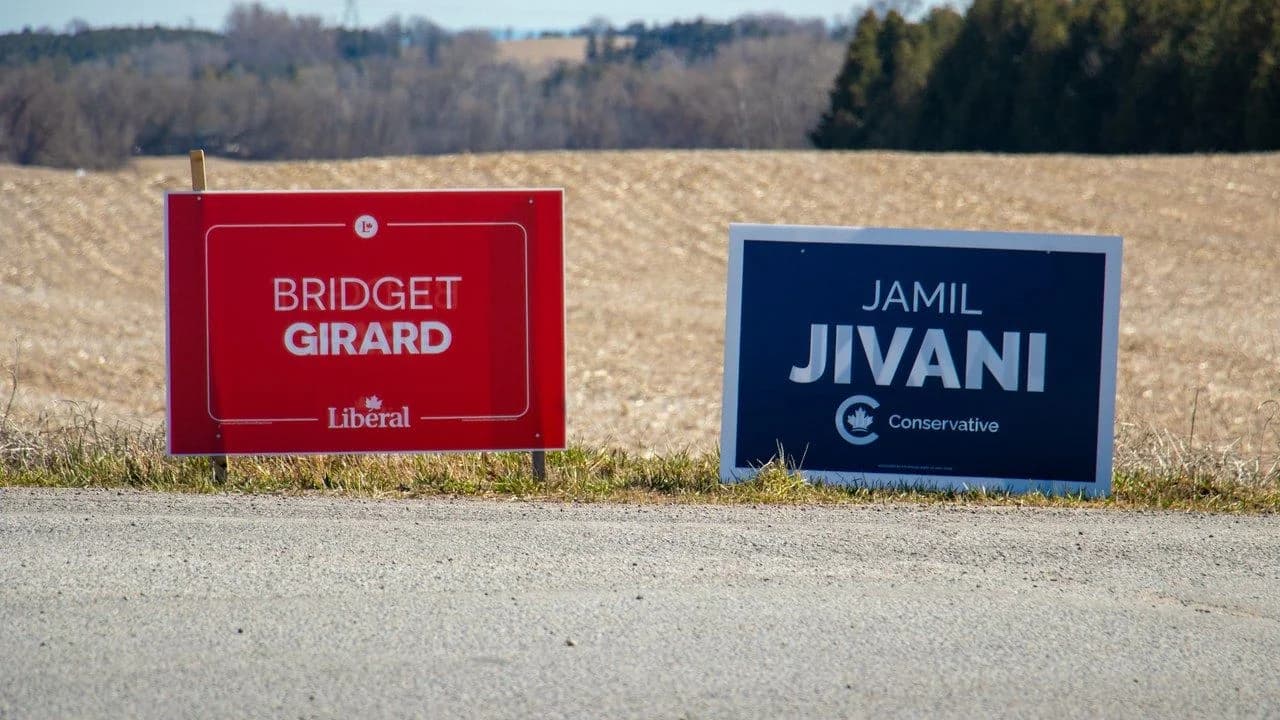 Two Canadian federal election campaign lawn signs beside a rural roadside in Clarington, Ontario; signs only, no people
