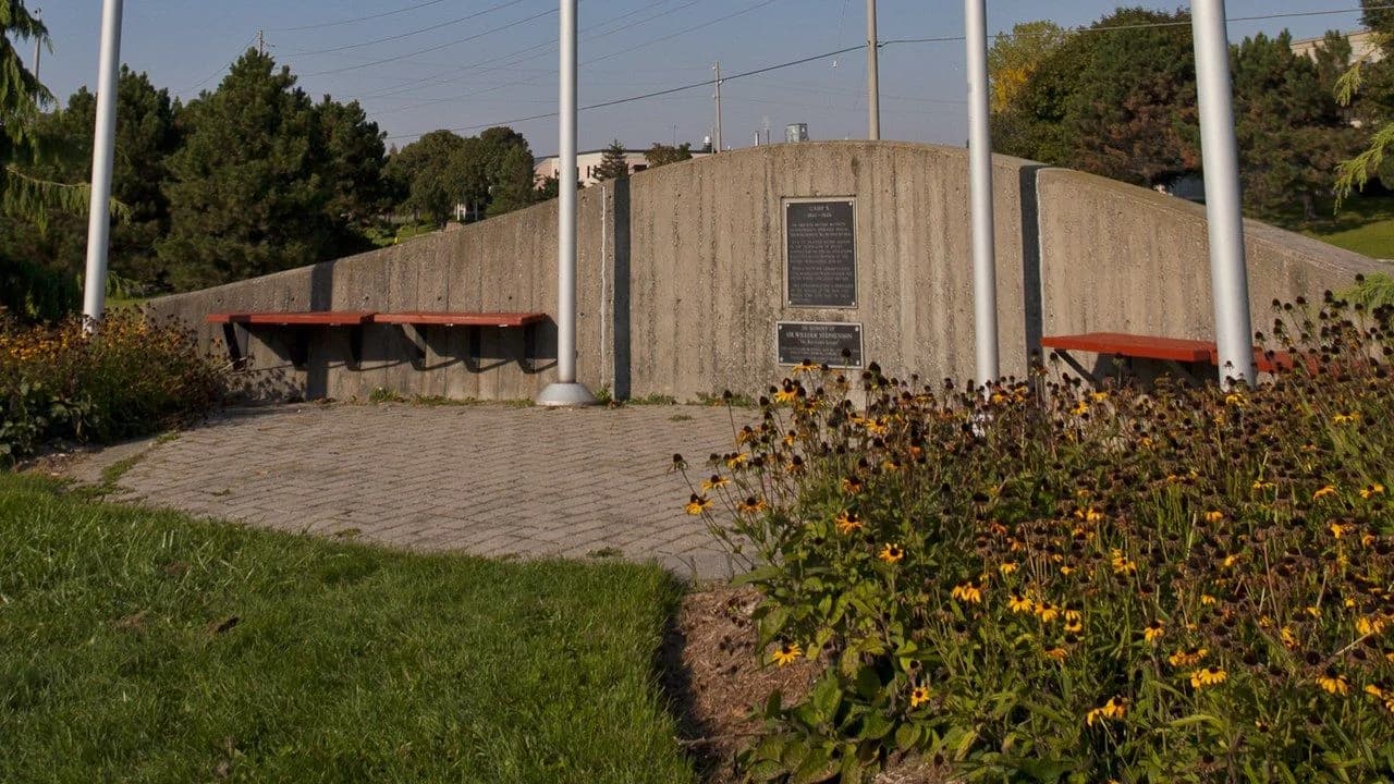 Stone Camp X memorial wall with plaques, flagpoles and benches at Intrepid Park in Whitby, Ontario