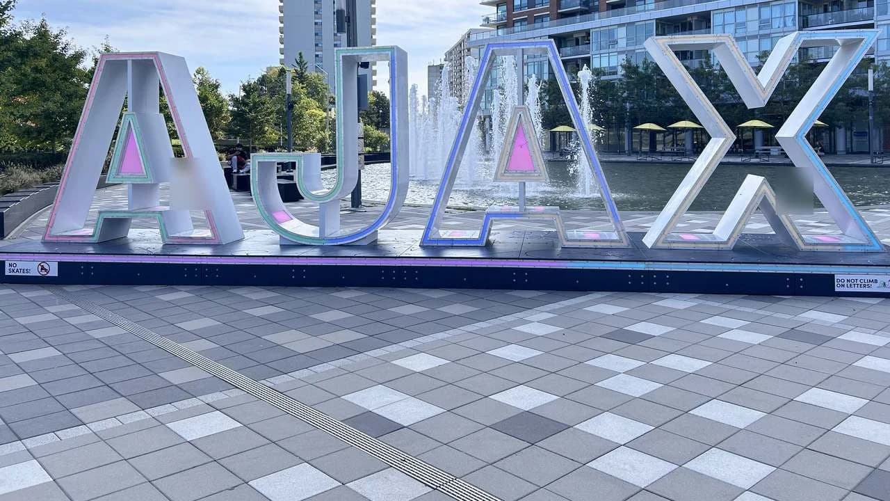 The large AJAX letters at Pat Bayly Square in Ajax, Ontario, with a fountain behind them; file photo, no people visible.