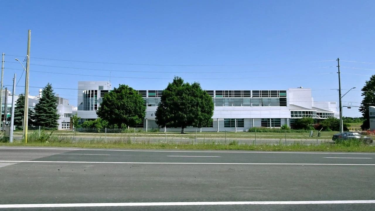 Exterior of a Durham College campus building in Whitby, Ontario — a modern low-rise building with trees in front; no people visible.