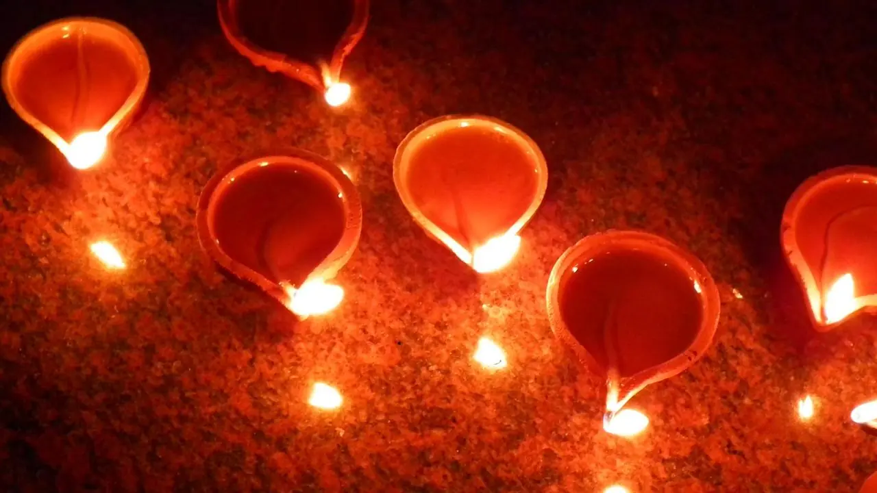 Lit traditional clay oil lamps (diyas) with glowing flames; no people visible.